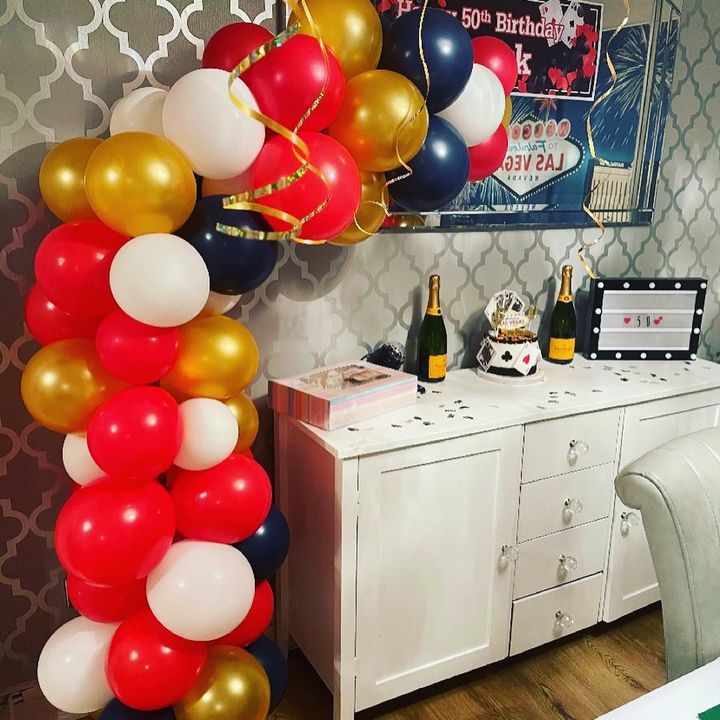 living room scene with celebration balloon arch on display of red, white and black balloons for a birthday party