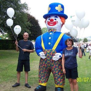 giant inflatable clown and performers with balloons at children's festival event in field
