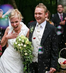 male and female wedding couple in bridal dress being showered in wedding rice confetti