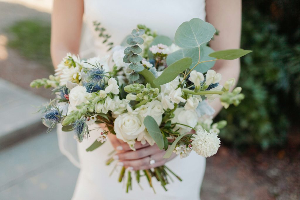 Wedding bouquet of white flowers and green foliage in a brides hands