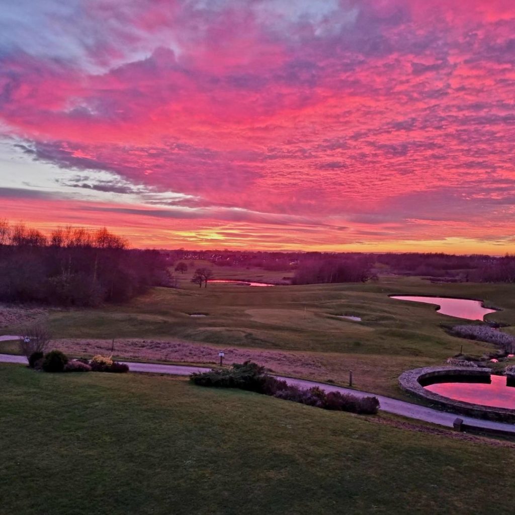 North west wedding venue Wychwood Park hotel view of golf course at sun set with pink and purple sky
